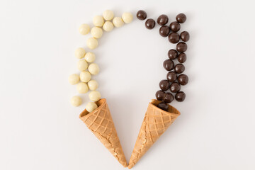 Cornet and contrast between black and white chocolate balls. Minimal flat lay.