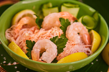 Prawns with vermicelli, lying in a bowl in a restaurant. Funchosa vermicelli (glass noodles) with seafood and lemon, salt and spices scattered on the table