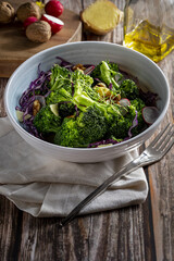 Plate with a healthy vegetarian salad of steamed broccoli, fresh radishes, walnuts, red cabbage, ginger and extra virgin olive oil. Mediterranean diet food. With copy space.