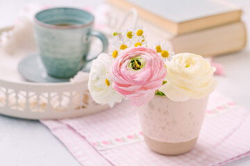 Beautiful tender blossoming of fresh cut bouquet with cup of tea nad books in background