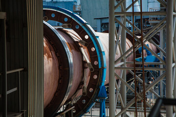 Standard Cement plant. Close up of rotary clinker kiln. Rusted tube and blue gear.