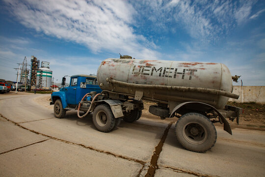 Standard Cement plant. Truck with dry cement on blue sky background. Title on cistern: Cement.
