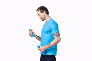 a man doing exercises with dumbbells on a light background in a blue t-shirt and pants