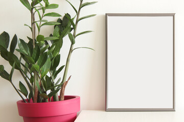 blank picture frame with green Zamia plant in pot