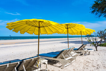 Beach chairs and Yellow Umbrellas on the beach thailand in the hot sun during the day