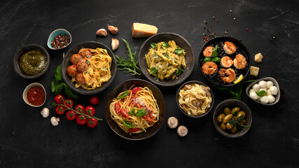 Assortment of Italian pasta with traditional sauces for dinner on dark background.