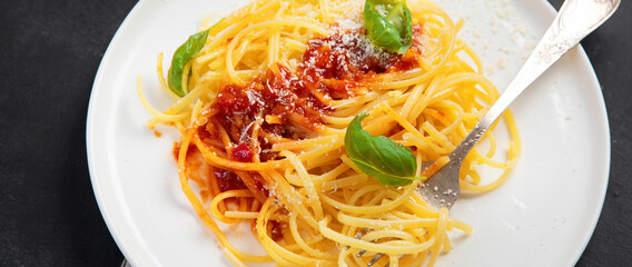 Delicious appetizing Italian pasta spaghetti with tomato sauce, parmesan and basil on a plate on a gray background. Top view, copy space