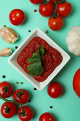 Bowl of tomato paste and ingredients on mint background