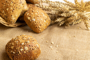 Home baked bread. Rye bakery with crusty loaves and crumbs. Fresh rustic traditional bread with wheat grain ear or spike plant on natural cotton background. Design element for bakery product label.