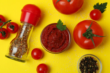 Bowl of tomato paste and ingredients on yellow background, top view