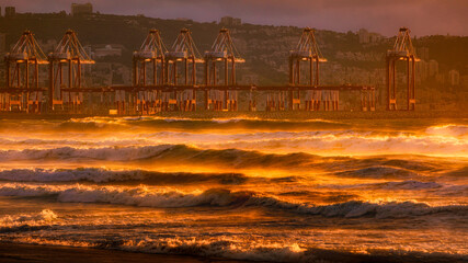 Haifa Cargo Port at Sunset with waves in front at golden color