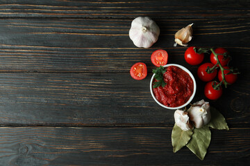 Bowl with tomato paste, tomatoes and garlic on wooden table