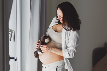 Pregnant woman with toy listening baby