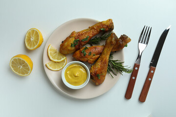 Concept of delicious eating with plate of roast chicken drumsticks on white background