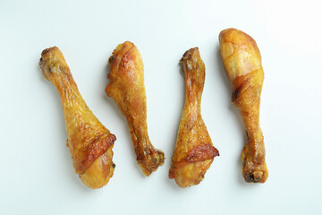 Four roast chicken drumsticks on white background