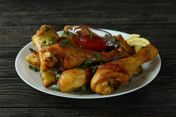 Concept of delicious eating with plate of roast chicken drumsticks on wooden background