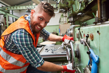 Arbeiter in Metallfabrik bedient Standbohrmaschine