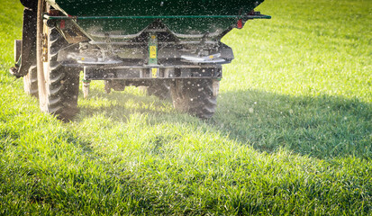 Tractor spreading artificial fertilizers in field