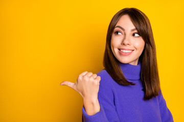 Photo of pretty charming young woman wear purple pullover pointing looking back empty space isolated yellow color background