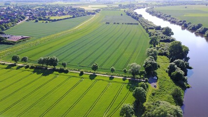 aerial view of farmland with tractor lanes and trees and a river