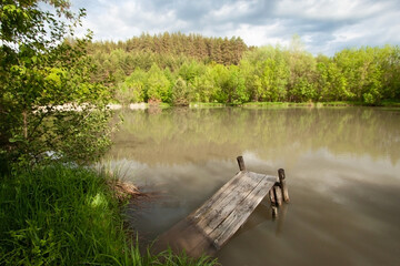 Wooden bridge by the lake. From old age, the bridge fell into the water. In the background is a...