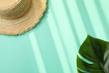 Straw hat and palm leaf on mint background