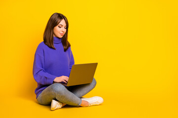 Naklejka premium Portrait of pretty focused girl sitting in lotus pose using laptop writing e-mail copy space isolated on bright yellow color background