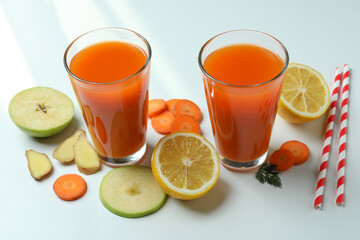 Glasses of juice and ingredients on white background