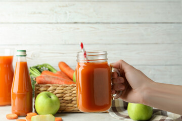 Female hand hold jar with apple - carrot juice
