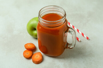 Glass jar of juice and ingredients on white textured background