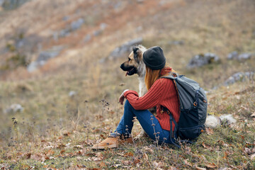Naklejka na ściany i meble woman hiker next to a dog in the mountains on nature vacation landscape