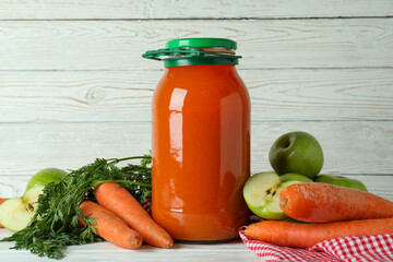 Jar of apple - carrot juice and ingredients on white wooden background