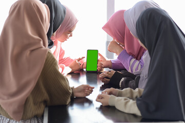 Young asian teenager sitting at cafe looking at blank phone screen together for copy space