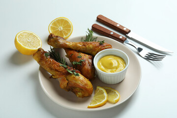 Concept of delicious eating with plate of roast chicken drumsticks on white background