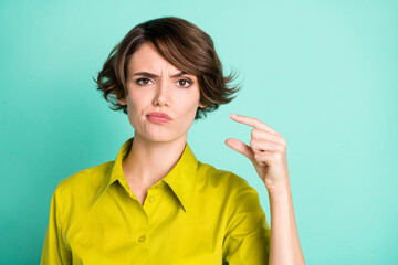 Photo portrait of unhappy girl showing small size fingers isolated on bright turquoise color background