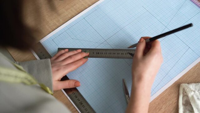 Top view of female hands are drawing design of a new collection of lingerie. Workplace of a professional designer. Copy space.