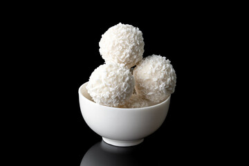 coconut candies in white cup isolated on black background