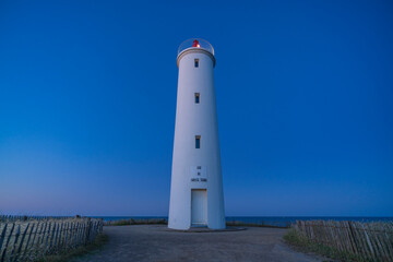 Fototapeta na wymiar Beautiful lighthouse on the French west coast during blue hour at night in the sunrise at summertime with a blue sky without any cloud. The inscription 