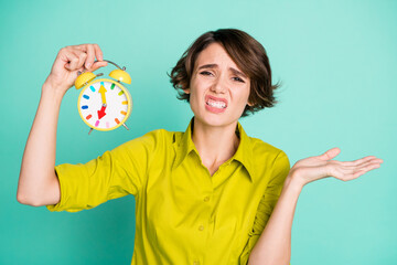 Photo portrait of grumpy female worker showing alarm clock deadline is near isolated on vivid turquoise color background