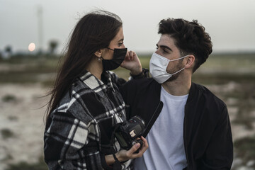 Shallow focus shot of a cute Spanish Caucasian couple wearing facemasks, the new normal