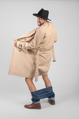 Exhibitionist exposing naked body under coat on light background