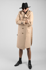 Exhibitionist in coat and hat on light background