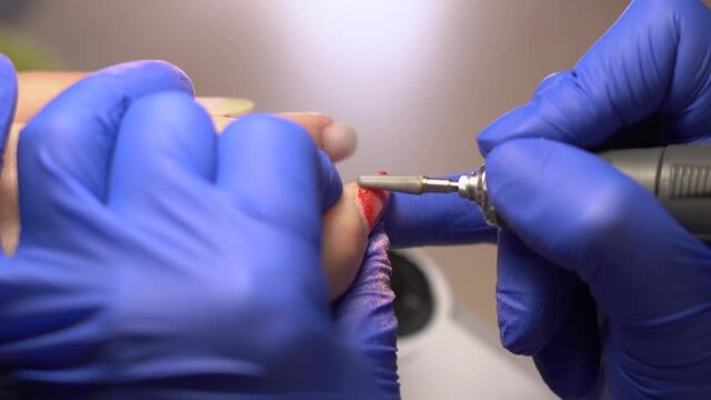 Closeup view 4k stock video footage of hands of woman undergoing beauty procedures in professional modern nailsalon. Manicurist doing manicure and polishing nails in pastel pink nude trendy color