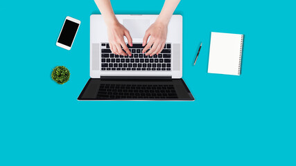 Fototapeta na wymiar Top view Flat lay.Overhead shot of female hands using laptop on blue office desktop. Business background.