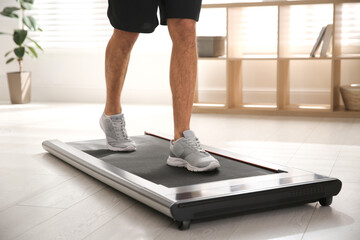 Sporty man training on walking treadmill at home, closeup © New Africa