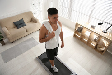 Fototapeta premium Sporty man training on walking treadmill at home