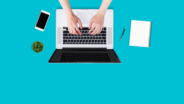 Top view Flat lay.Overhead shot of female hands using laptop on blue office desktop. Business background.