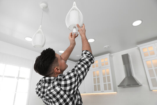 Man Changing Light Bulb In Lamp At Home