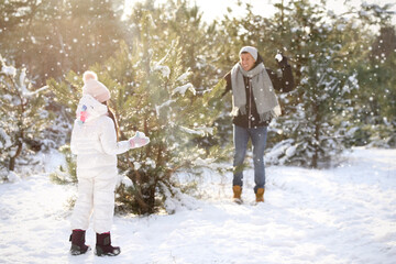 Father and daughter having snowball fight outdoors on winter day. Christmas vacation