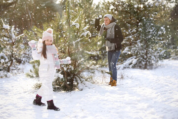 Fototapeta na wymiar Father and daughter having snowball fight outdoors on winter day. Christmas vacation